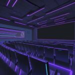 Diverse students in a modern lecture hall watch a glowing neural network architecture displayed on a large projection screen.